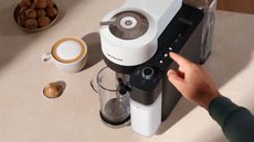 Best coffee maker deals: A birdseye view of the Nespresso lattissima one coffee maker on a countertop with coffee and a pod at the side